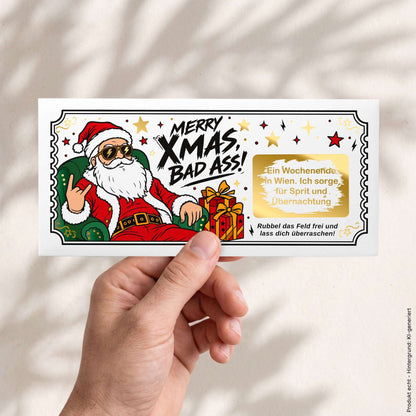 Hand hält Rubbelkarte Merry Xmas Bad Ass mit Wunschtext Wochenendtrip im goldenen Rubbelfeld – DIN lang – KuschelICH