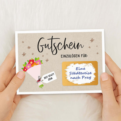 Rubbel Gutschein Blumenstrauß Gutschein mit goldfarbenem Rubbelfeld in den Händen gehalten