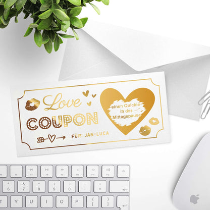 Weißer personalisierter Love Coupon mit goldener Folierung und Umschlag im Hintergrund