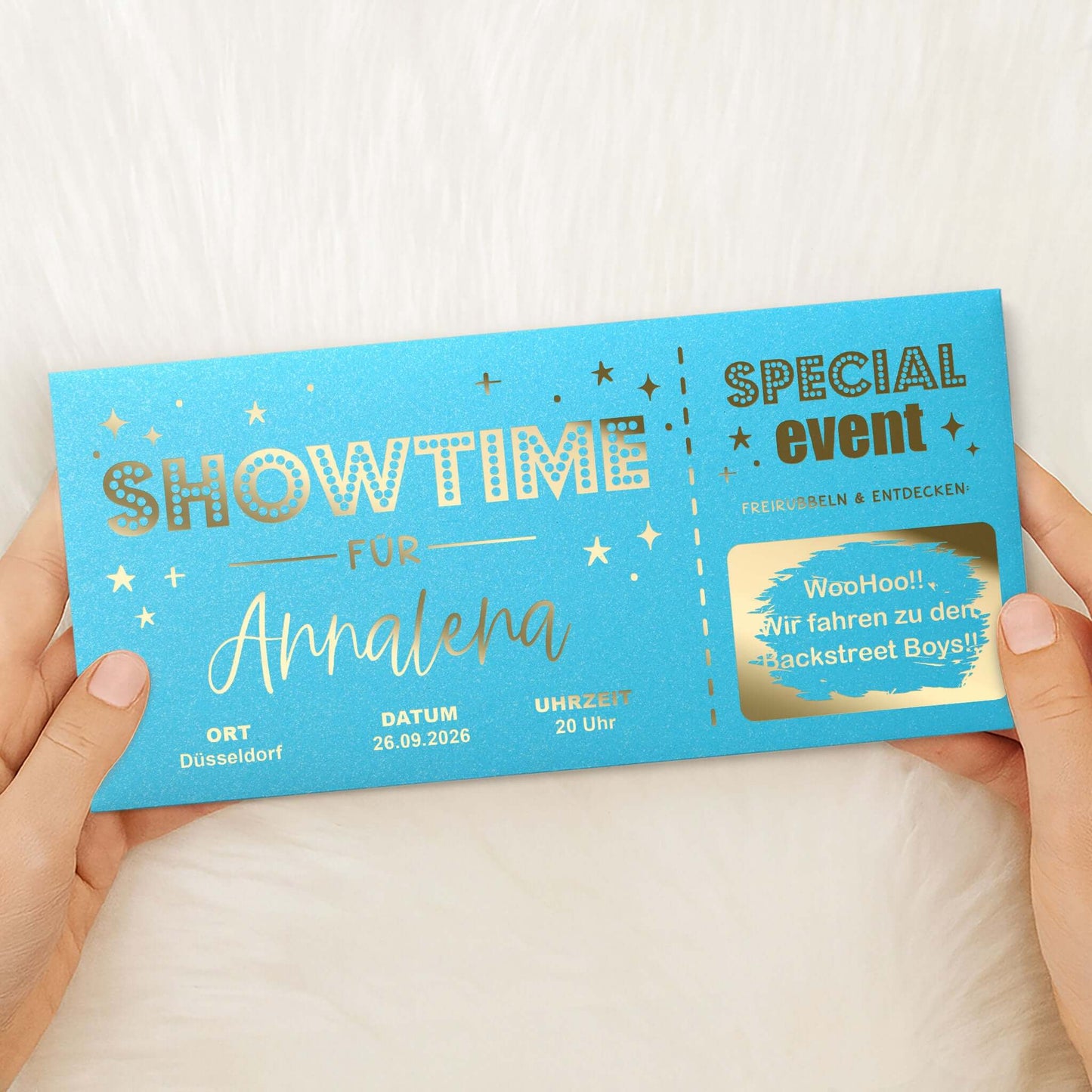 Rubbelkarte Showtime Aqua Schimmer mit Goldfolierung, von zwei Händen gehalten – Lifestyle