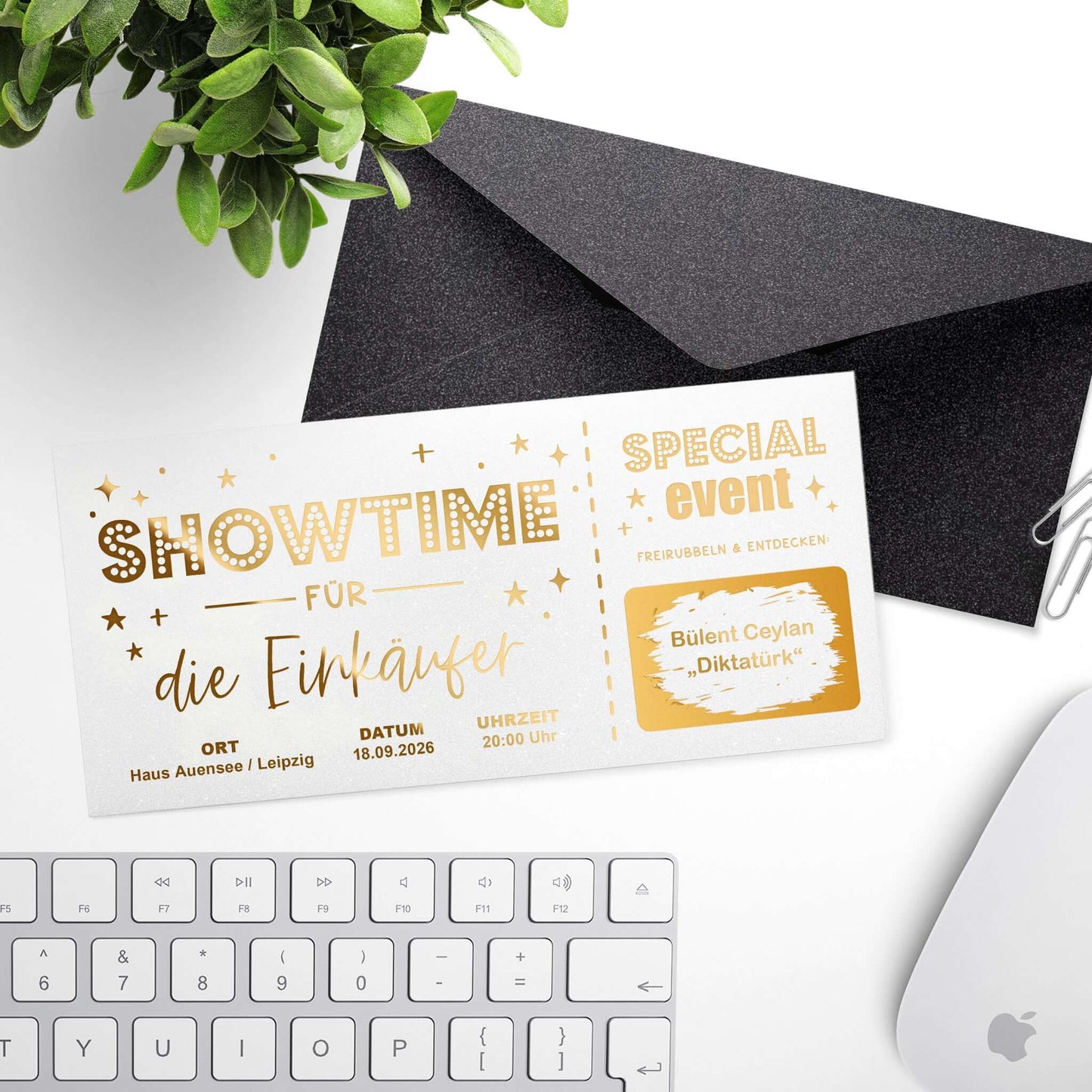 Rubbelkarte Showtime Weiß Schimmer mit Goldfolierung und schwarzem Umschlag, Desktop-Setting mit Pflanze