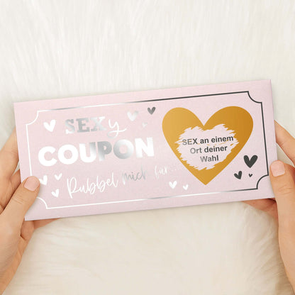 Rubbelkarte personalisiert in Händen, Gutschein für Paare mit Aufschrift SEX an einem Ort deiner Wahl.